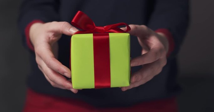 female teen girl shows green gift box with red ribbon and a bow