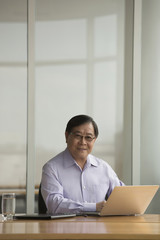 Fototapeta na wymiar Singapore, Senior businessman using laptop at desk