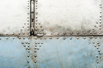 Old blue and silver metal surface of the aircraft fuselage with rivets