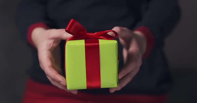 female teen girl shows green gift box with red ribbon and a bow