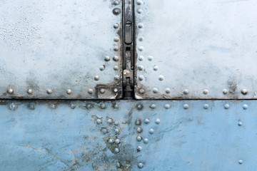 Old blue and silver metal surface of the aircraft fuselage with rivets