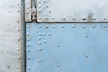 Old blue and silver metal surface of the aircraft fuselage with rivets