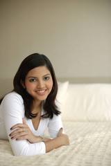 Woman lying on bed, arms crossed, smiling