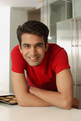 Man leaning on kitchen counter, looking at camera