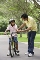 A father teaches his son to ride a bike