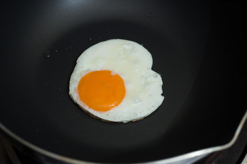 Fried egg on pan and fresh eggs.