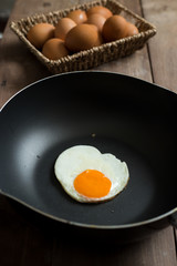 Fried egg on pan and fresh eggs.