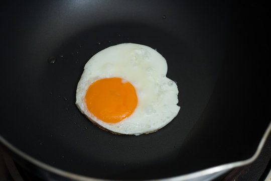 Fried egg on pan and fresh eggs.