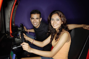 Fototapeta na wymiar Couple in a video game arcade, playing games, smiling at camera