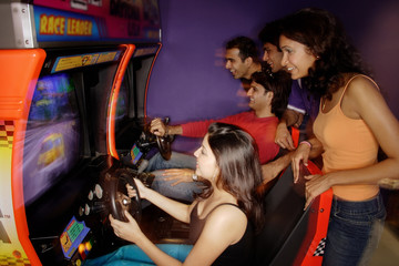 Young adults playing games in amusement arcade