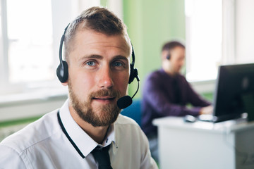Businessman in the office on the phone with headset, looking camera