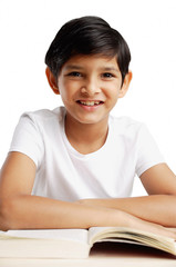 Boy leaning on book, smiling at camera