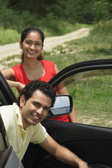 Young couple with car smiling at camera