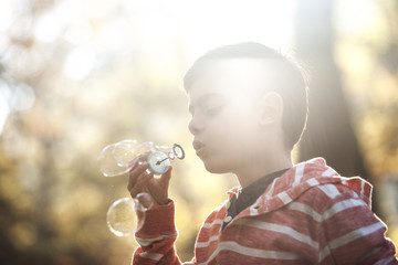 Little boy blowing soap bubbles in the park