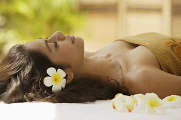Obraz na płótnie Canvas A woman lying down with frangipani flowers around her