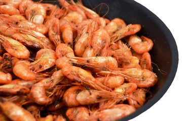 Black Sea shrimps, fried in black cast iron skillet. Isolated on white background, closeup. Focus in center