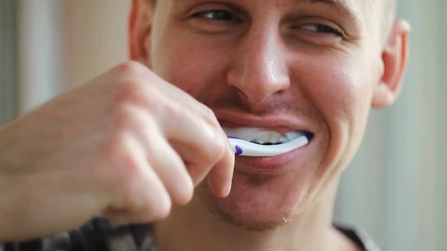 young man brushing his teeth in the morning