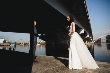 young groom and his  bride   walk by the river