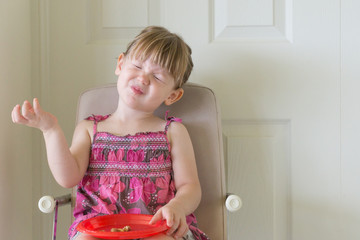 Little girl tasting food and making funny face
