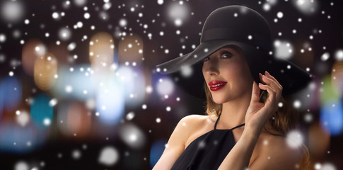 beautiful woman in black hat over night lights