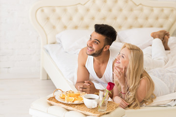 Obraz na płótnie Canvas Young Couple Lying In Bed Eat Breakfast Morning With Red Rose Flower, Happy Smile Hispanic Man And Woman Lovers In Bedroom