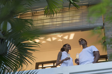 Singapore, Two young people standing on balcony, holding champagne