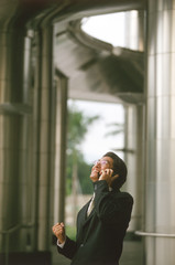 Male executive talking on cellular phone, office building behind