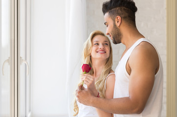 Young Beautiful Couple Stand Near Big Window, Hispanic Man Give Woman Red Rose, Happy Smile Lovers