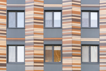 Fototapeta premium Grey and brown facade of the building with windows, background