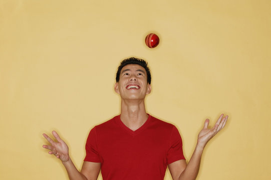 Young Man Juggling A Ball, Yellow Background