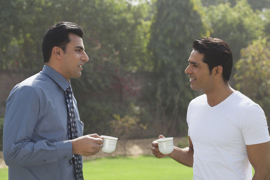 India, Two Men In Garden Drinking Coffee And Talking