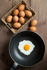 Fried egg on pan and fresh eggs.