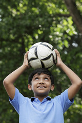 Young boy balances ball on his head