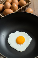 Fried egg on pan and fresh eggs.