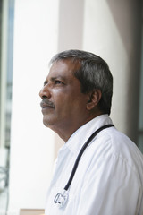 Head shot of Indian doctor looking up and thinking