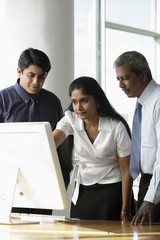 Indian woman looking at a computer with male colleagues