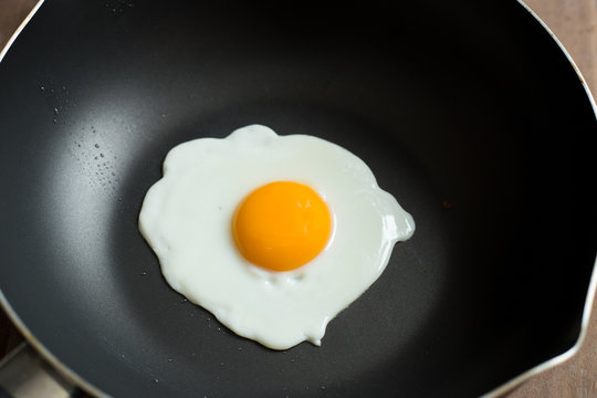 Fried egg on pan and fresh eggs.