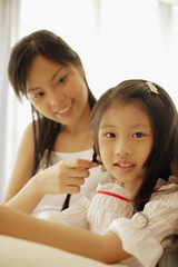 Fototapeta premium Mother braiding her daughter's hair.