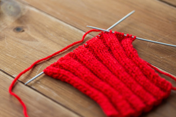 hand-knitted item with knitting needles on wood