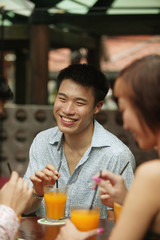 Young man sitting with friends, having a drink