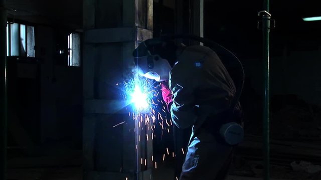 Medium shoot of craftsman and welding arc, He is working with structural concrete restoration.