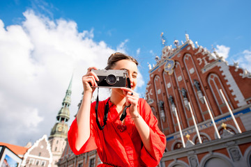 Portrait of a young female tourist with photo camera on the main old town square in Riga. Woman...