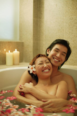 Obraz na płótnie Canvas Couple hugging in tub, smiling.