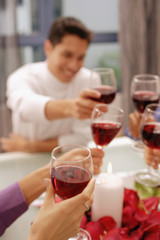 Friends toasting with wine glasses across dinner table