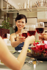 Friends toasting wine glasses across dinner table