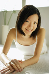 Naklejka premium Young woman lying on front, looking at camera