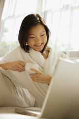 Young woman drinking coffee, laptop open in front of her