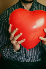 Hombre joven sujetando un globo con forma de corazón 