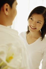 Man with flowers behind his back, facing woman