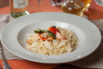 Pasta with cheese, vegetables and seafood in white plate